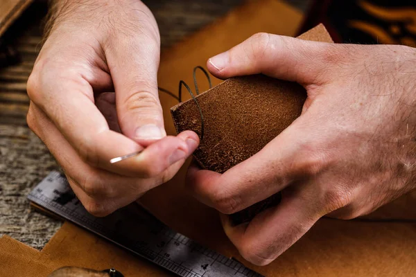 Sluiten van een schoenmaker of ambachtelijke arbeider handen. Lederen handwerktuigen op oude houten tafel. Werkplaats voor leerambacht. — Stockfoto