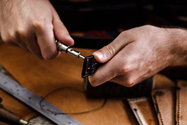 Ayakkabıcı ya da zanaatkar işçilere yakın çekim. Eski ahşap masadaki deri el aletleri. Deri sanatları atölyesi.