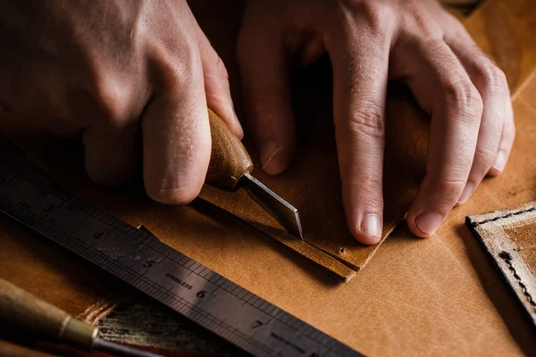 Großaufnahme der Hände eines Schuhmachers oder Handwerkers. Handwerkzeuge aus Leder auf altem Holztisch. Werkstatt für Lederhandwerk. — Stockfoto