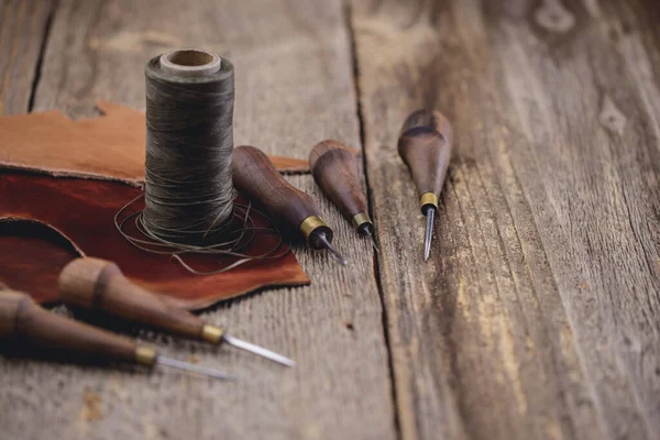 Шкіряні інструменти для ремесел на старому дерев'яному столі. Шкіряна майстерня ремесел . — стокове фото