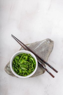 Beyaz masanın üzerinde susam tohumu olan yosun salatası. Geleneksel Asya yemekleri.