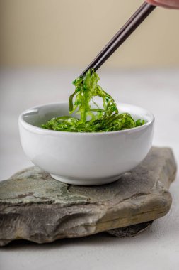 Beyaz masanın üzerinde susam tohumu olan yosun salatası. Geleneksel Asya yemekleri.