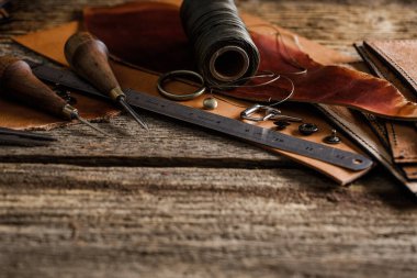 Kulübedeki eski ahşap masada deri el işi aletleri. Deri ustası çalışma alanı. Koyu ahşap dokusunu öğüt.