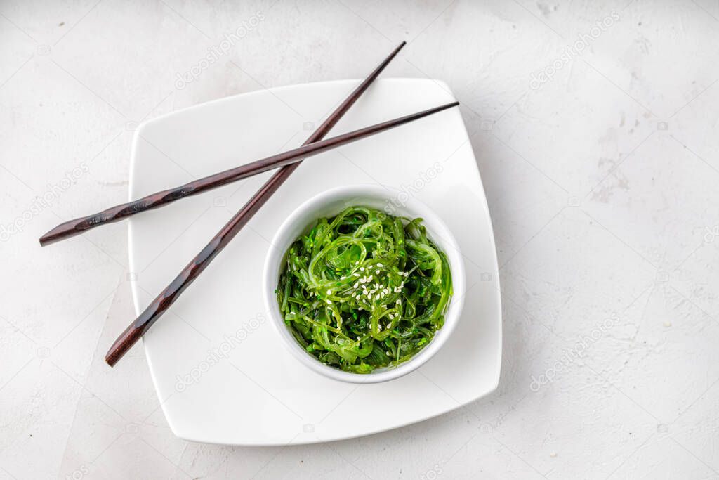 Croped photo of green wakame seaweed salad with chopstick at the restaurant