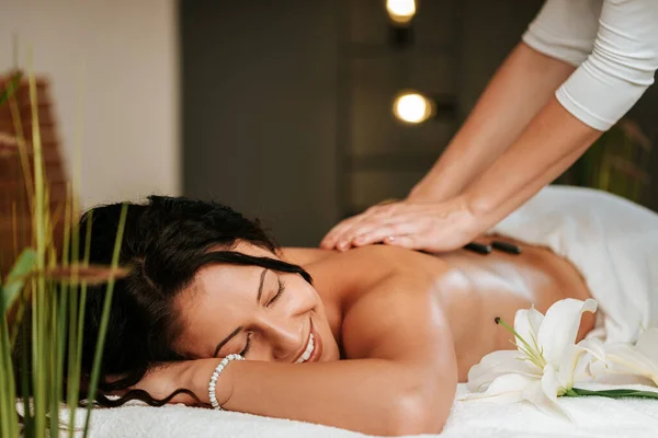 Mulher bonita no salão de massagem com cabelo encaracolado marrom e pele saudável. Conceito de massagista e paciente. — Fotografia de Stock