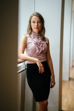 bir genç, uzun boylu, çekici sarışın beyaz bir kadın portresi. O profesyonel ofis kıyafet ve poz giyinmiş 