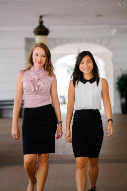 İki iş (bir Çinli Asyalı kadın ve beyaz bir kadın) farklı bir takım portresi. Rahat bir şekilde gülümsüyor musun.