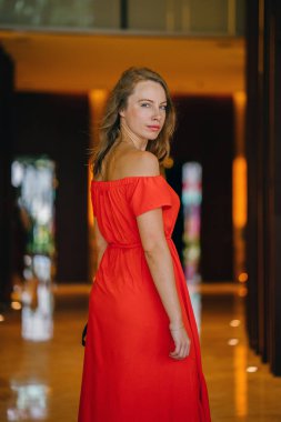 Bir turuncu yaz elbise poz içinde bir genç, çekici Avrupa kadın portresi. O yeşil gözlü sarışın ve güvenle gülümseyen.