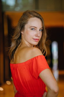 Bir turuncu yaz elbise poz içinde bir genç, çekici Avrupa kadın portresi. O yeşil gözlü sarışın ve güvenle gülümseyen.