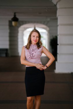 Şehirde poz beyaz beyaz bir kadın portresi. O profesyonel ofis kıyafet ve gülümseyen giymiş 