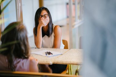 İki kadın meslektaşları gündüz ofiste iş tartışma var. Çinli Asyalı kadın ve diğer bir beyaz beyaz kadın.