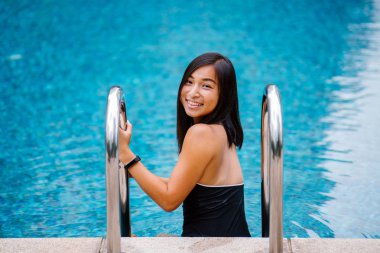 Bir havuzdan bir güneşli hafta sonu kaçamağı üzerinde yüzmek sonra bir merdiven tırmanma bir sevimli, çekici genç Çinli Asyalı kadın portresi. O uygun, tabaklanmış tonda ve ve gülüyor