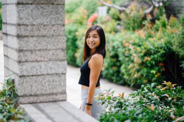 Çekici, genç Çinli Asyalı bir kadın portresi sportif, aktif giyim yeşil Parkı Singapur hafta sonu gün içinde giyinmiş.