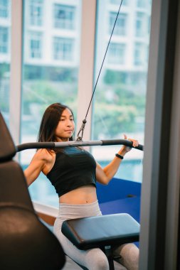 Spor salonunda egzersiz genç bir Çinli Asyalı kadın portresi. O ağır ağırlıklar ile çalışıyor ve yalın, tabaklanmış, tonda ve kaslı bir kız. Onun iş günü çok odaklı.