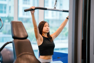 Spor salonunda egzersiz genç bir Çinli Asyalı kadın portresi. O ağır ağırlıklar ile çalışıyor ve yalın, tabaklanmış, tonda ve kaslı bir kız. Onun iş günü çok odaklı.