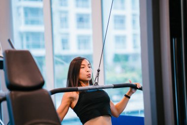 Spor salonunda egzersiz genç bir Çinli Asyalı kadın portresi. O ağır ağırlıklar ile çalışıyor ve yalın, tabaklanmış, tonda ve kaslı bir kız. Onun iş günü çok odaklı.