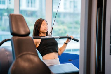 Spor salonunda egzersiz genç bir Çinli Asyalı kadın portresi. O ağır ağırlıklar ile çalışıyor ve yalın, tabaklanmış, tonda ve kaslı bir kız. Onun iş günü çok odaklı.