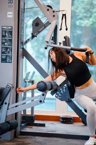 Spor salonunda egzersiz genç bir Çinli Asyalı kadın portresi. O ağır ağırlıklar ile çalışıyor ve yalın, tabaklanmış, tonda ve kaslı bir kız. Onun iş günü çok odaklı.