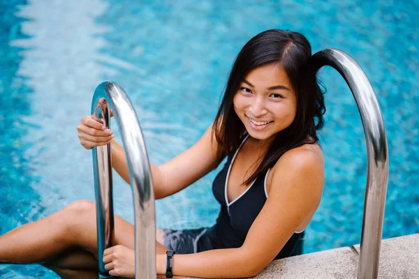 Bir havuzdan bir güneşli hafta sonu kaçamağı üzerinde yüzmek sonra bir merdiven tırmanma bir sevimli, çekici genç Çinli Asyalı kadın portresi. O uygun, tabaklanmış tonda ve ve gülüyor