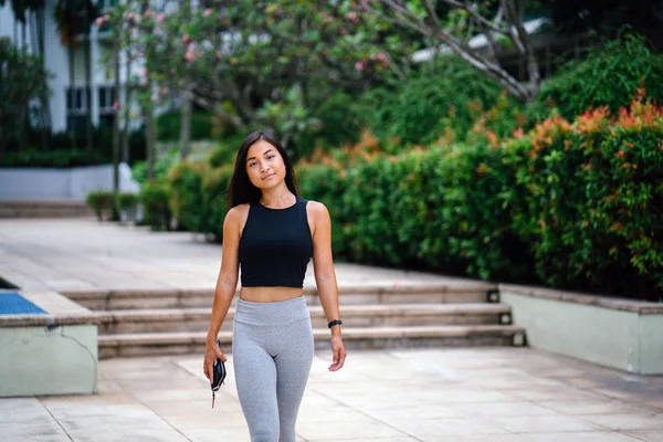 Çekici, genç Çinli Asyalı bir kadın portresi sportif, aktif giyim yeşil Parkı Singapur hafta sonu gün içinde giyinmiş.