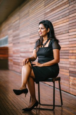 Gün ofisinde bir koridor bir sandalyede oturan bir Hint Asya iş kendine güvenen, başarılı ve çekici kadın portresi. Onun profesyonel çekim için gülümsüyor