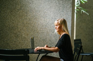 Bir kafede onu notebook laptop üzerinde gün boyunca çalışan bir genç ve çekici sarışın iş kadın portresi. O oturuyor ve o üzerinde yaptığı çalışmalar odaklanır smiling.