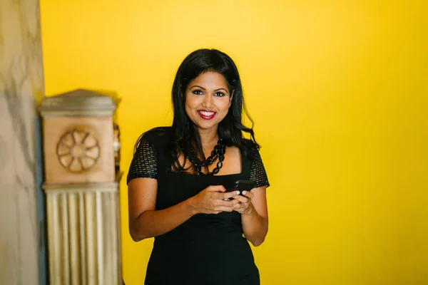 Portrait of a young but mature and confident Indian Asian woman using her smartphone during the day