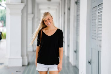 Asya'da bir koloni binanın bir koridorda duran genç, çekici sarışın turist portresi. 