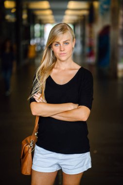 Ayakta ve gün boyunca şehrin Asya bir kampüste bir koridorda gülümseyen mavi gözlü genç ve güzel sarışın kadın öğrenci portresi. O raslantı ışık kılığına girmiş.