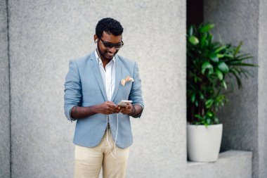 Serin bir portresi Hint Asya adam gün. O sıradan bir takım elbise ve güneş gözlüğü. O güneşin altında uzanmanız ve birini bekliyor gibi bir spor çantası elinde.