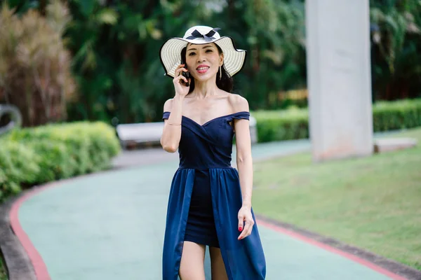 드레스와 스마트폰으로 공원에 모자에 아시아 여자의 초상화 — 스톡 사진