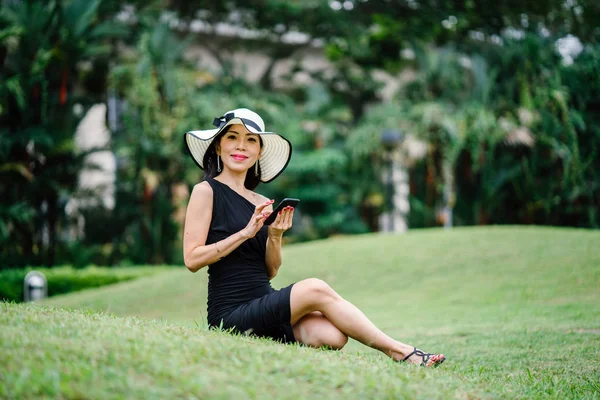 드레스에 아시아 여자와 스마트폰으로 공원에서 모자의 초상화 — 스톡 사진