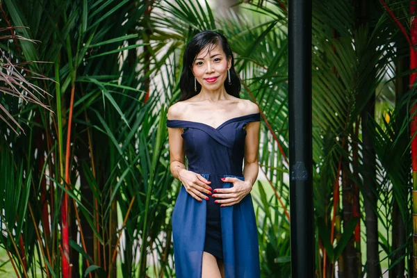 亚洲华人女子的肖像在一天中的一个优雅的蓝色礼服摆在一个公园里 — 图库照片