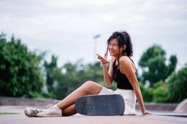 Cep telefonu ve paten skatepark Asyalı Çinli Kız portresi