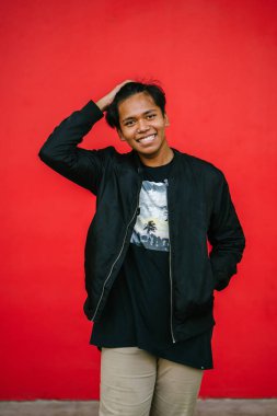 saçları dokunmadan kırmızı arka plan üzerinde ayakta gülümseyen yakışıklı adam portresi