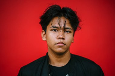 Genç yakışıklı adam ayakta kırmızı zemin üzerine poz portresi