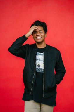 saçları dokunmadan kırmızı arka plan üzerinde ayakta gülümseyen yakışıklı adam portresi