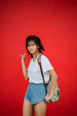 Kırmızı studio arka plan üzerinde poz sırt çantası ile şık Asyalı kız