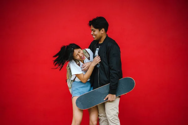 Heureux Jeune Couple Amuser Debout Sur Fond Rouge Avec Skateboard — Photo