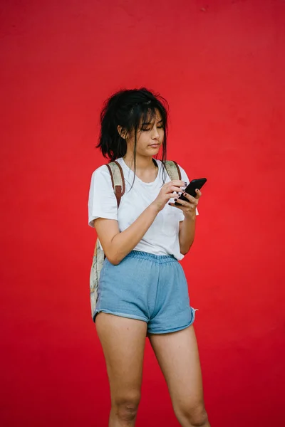 Bela Asiático Menina Sorrindo Segurando Smartphone Estúdio Vermelho Fundo — Fotografia de Stock