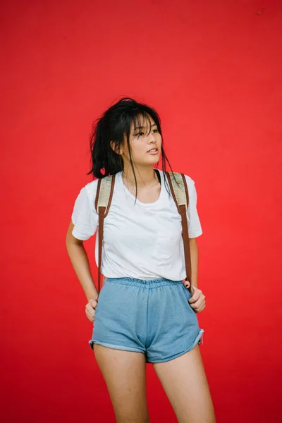 Elegante Asiático Chica Con Mochila Posando Rojo Estudio Fondo —  Fotos de Stock