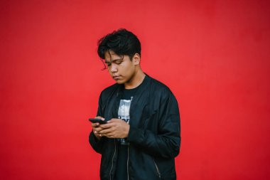 yakışıklı delikanlı ile smartphone kırmızı arka plan üzerinde duran