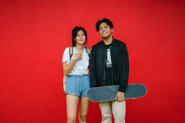 Stylish Young Couple Standing Red Background Skateboard — Stock Photo, Image