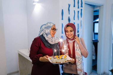 İki Müslüman Malay kadın kutluyor Doğum havai fişekleri ile pasta tutan gülümseyerek