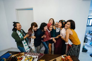 Asyalı kadınlar ayakta yakınındaki tablo atıştırmalık yiyecekler ve tatlılar ile gülüyor 
