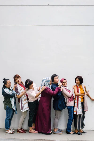 group of asian women having fun standing on white wall background, full length