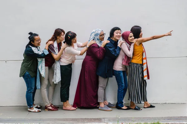 group of asian women posing having fun standing on white wall background, full length