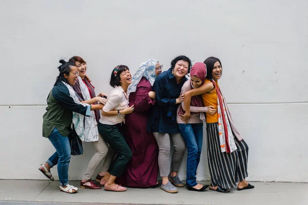 group of asian women having fun standing on white wall background, full length