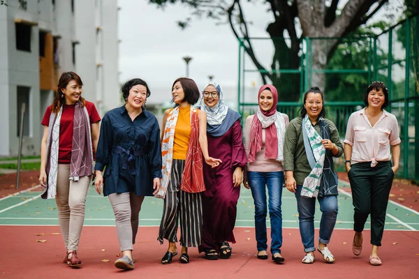 diverse group of asian women walking together on basketball court, full length