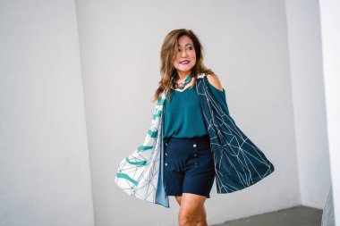 Trendy Yeşil bluz ve beyaz arka plan üzerinde duran Lacivert şort giyen olgun Asyalı kadın portresi